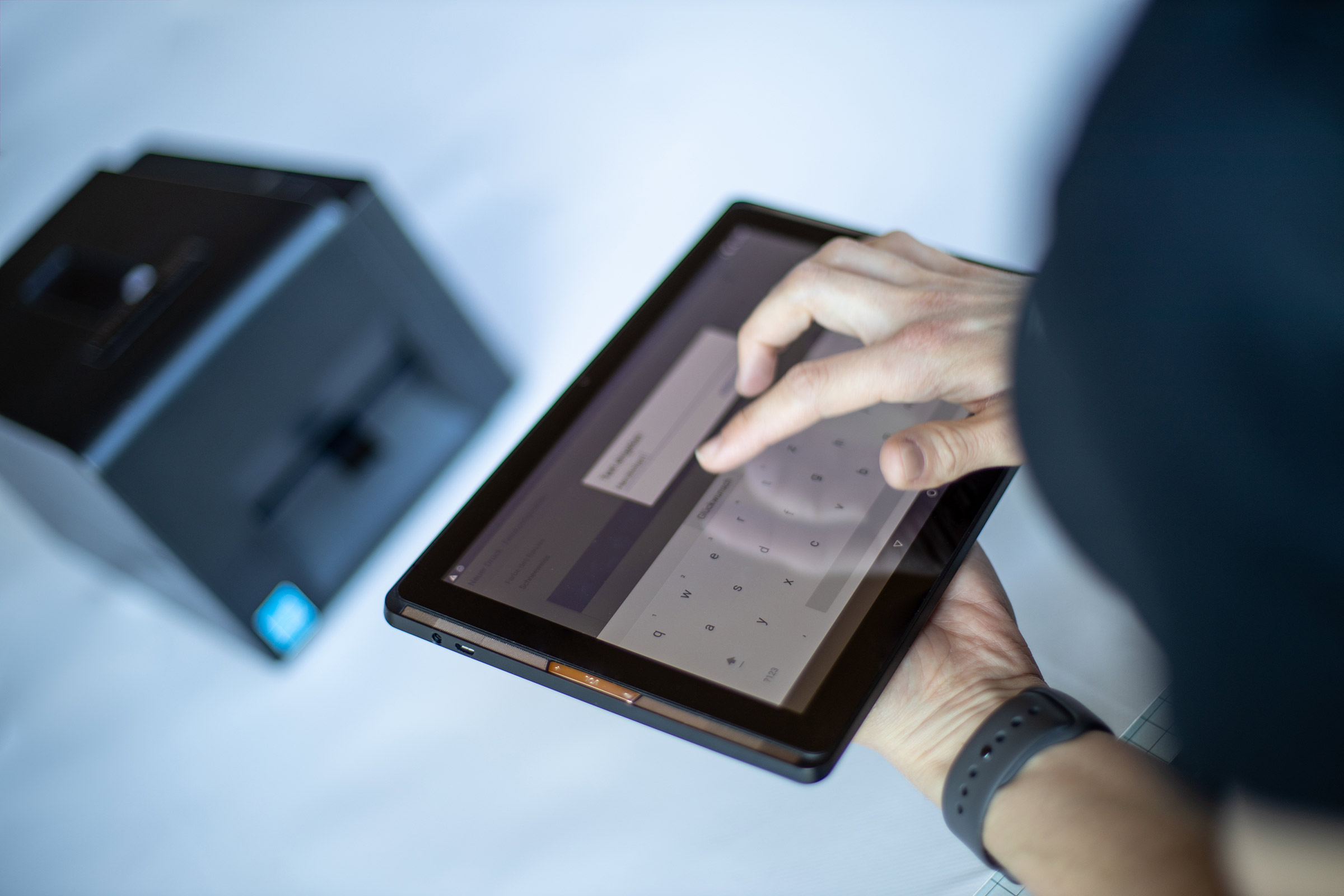 Einfach Schleifenband in der Schleifenfee-App designen und direkt drucken! Eine Frau, die auf einem Tablet in der Schleifenfee-App Text eingibt, der auf das Schleifenband gedruckt werden soll